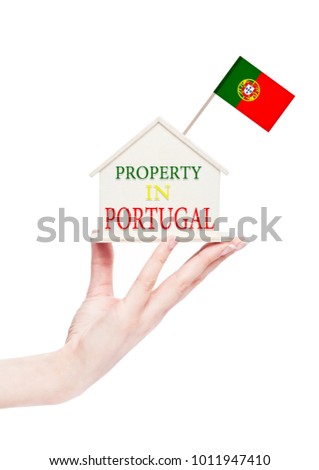 Female hand holding wooden house model with Portugal flag on top. Property in Portugal text 