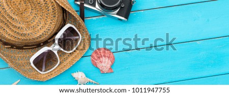Cover photo size summer background. Hat and sunglasses and seashells on blue wooden rustic background. Has copy space for text.