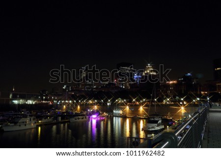 Montreal Downtown Panorama at night. Montreal reflected on the river at dusk with city lights and urban buildings. Night city lights. Quay in the colorful bright lights with rays. Old port montreal.