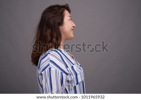 Studio shot of mature beautiful Asian businesswoman against gray background