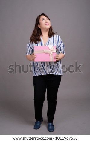 Studio shot of mature beautiful Asian businesswoman against gray background