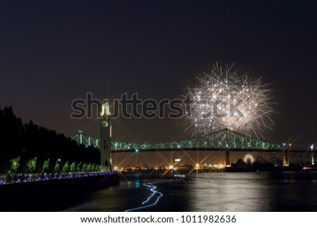 Montreal Clock Tower at night. Colorful fireworks explode over bridge, reflection in water. Montreal’s 375th anniversary. luminous colorful interactive Jacques Cartier Bridge. Old Port of Montreal.