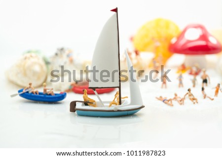 Miniature people: Sandy beach with tourists sail using as background traveling, exploring the world, business concept.