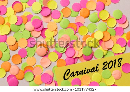 Carnaval party background concept, space for text. Written the words:  Carnival 2018. Colorful confetti spread over table. Warm colors: pink, yellow and orange.