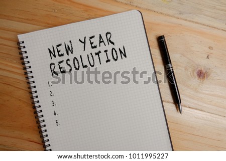 NEW YEAR RESOLUTION: Blank notepad and coffee cup on office wooden table
