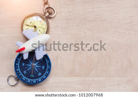 Travel and vacation plan background. Small airplane toy with pocket watch and compass on wood table. Vintage and retro filtered. Picture for add text message. Backdrop for design art work.