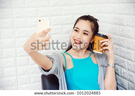 Young Asian Woman Using Smartphone to Selfie with Coffee Cup in Cafe