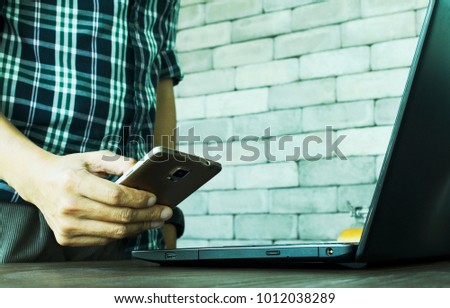 Hipster young man using smartphone and laptop computer for fintech concept backgrounds