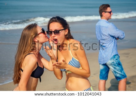 two beautiful and young women gossip about a man on the beach