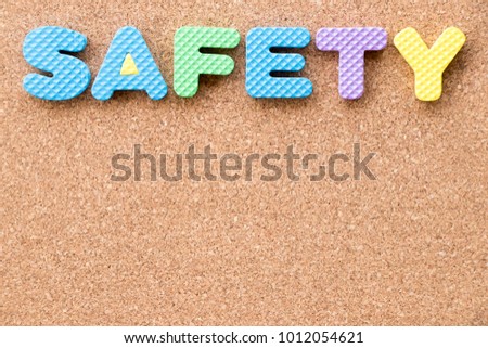 Color toy foam alphabet in word safety on cork board background