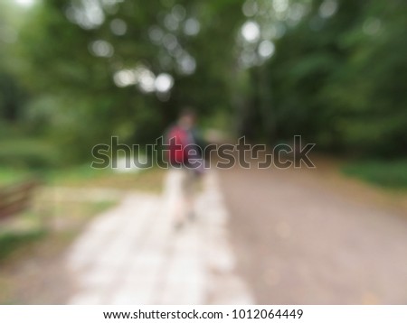 Blur photo one People walking in summer Park. Track among the trees in the Sunny glare. green backgrounds, abstract scenes with concept of healthy people, exercise in park.