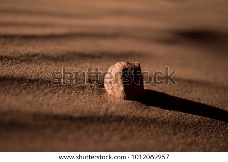 Picture was taken in the evening of a lone rock in the sand.