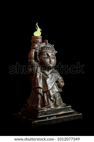 An unusual statue of freedom, a bronze statuette on a black background with a burning torch. New York, United States of America