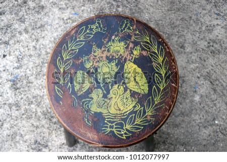 Antique circle wooden chair, color stamp to duck lotus and leaf picture, with concrete floor.