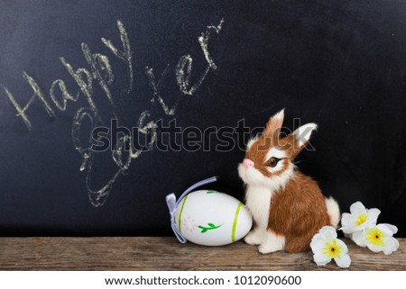 Toy rabbit, flowers and easter egg on a chalkboard background. Easter still life.Happy Easter.