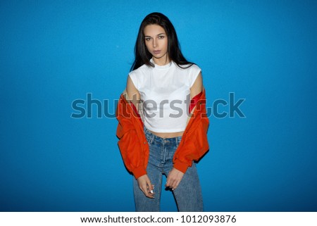 Young fashionable teenager woman near the blue wall