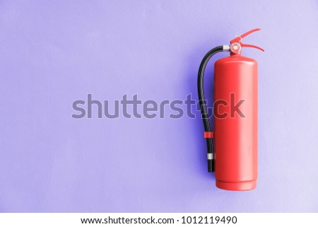 Fire extinguisher on the violet wall background.