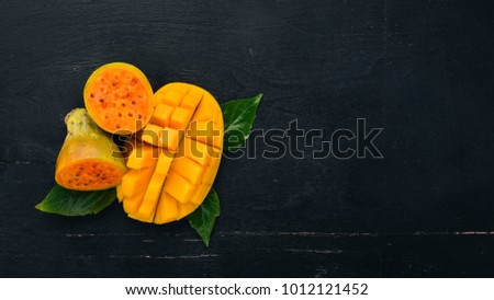 Mango and cactus fruit. Fresh Tropical Fruits. On a wooden background. Top view. Copy space.