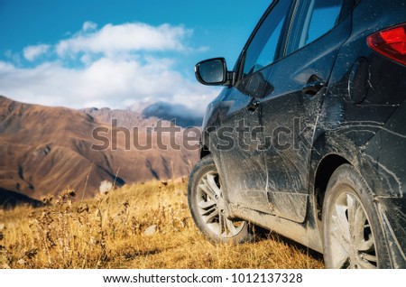 Off-road travel on car on mountain road against rocks in Caucasus, Georgia. Beautiful lights and colors at sunset
