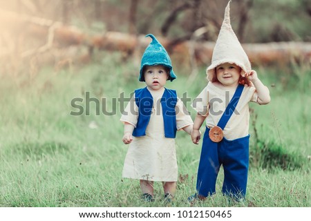 Two little gnomes have a nice time in a green forest. Childhood, happiness, summer concept