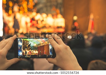 woman record concert on her phone while stand in crowd