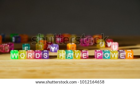 The phrase Words have power on a wooden surface of colored square blocks.