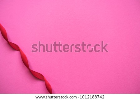 Colorful pink background with curly red ribbon. Valentine's Day, Wedding, Anniversary concept greeting card.