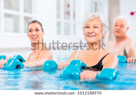 People young and senior in water gymnastics physiotherapy with dumbbells Royalty-Free Stock Photo #1012188970