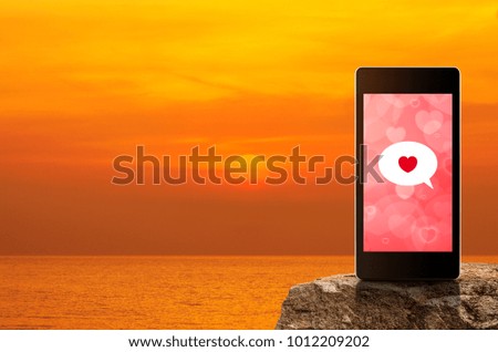 Love message on modern smartphone screen on rock over sunset sky and sea, Internet online connection, Valentines day concept