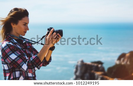Tourist traveler photographer making pictures sea scape on photo camera on background ocean, hipster girl look on nature horizon, relax holiday, blank space blue waves view, blurred backdrop for text
