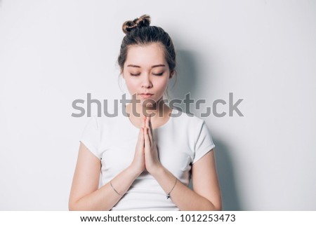 Praying young woman. Female with folded hands isolated on white