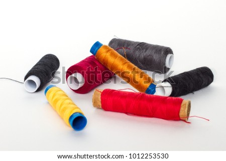 Spools of colored thread on a white background. Spool yellow, red, orange, gray and black threads.