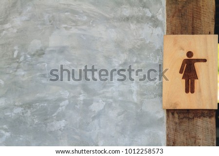 Wooden women public toilet sign with natural concrete loft style wall. Copy space.