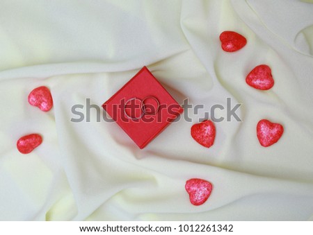 Light silk pleated red box . There are two wedding rings. Nearby is a lot of hearts.