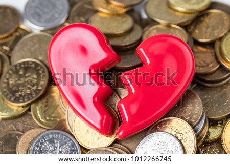 Broken red Valentines Day heart on a pile of coins. Love and money problems abstract concept.  Royalty-Free Stock Photo #1012266745