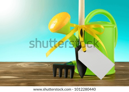 Different instruments for gardening and empty label with yellow ribbon