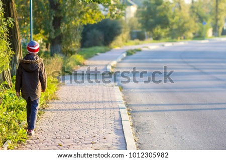 Child boy walking alone on a sidewalk Royalty-Free Stock Photo #1012305982