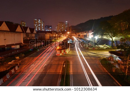 Tail light of cars on a freeway between buildings at night with motion blur