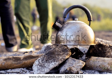 Stainless kettle on stone stove after camping of the tourist on the mountain in winter with blurry of people legs background.Concept is Lifestyle of travelers.Picture for journey  information.