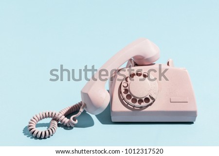 Oldschool pink telephone on a blue background. Telecommunication. Vintage objects. Royalty-Free Stock Photo #1012317520
