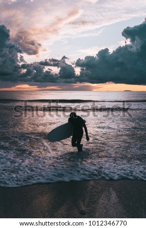 A surfer ending his surf session at sunset 