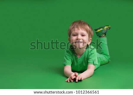 Happy boy in green clothes posing at camera against green background  Royalty-Free Stock Photo #1012366561