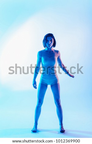 Modern teen contemporary dancer poses in front of the studio background in blue tones. in the front view vertical