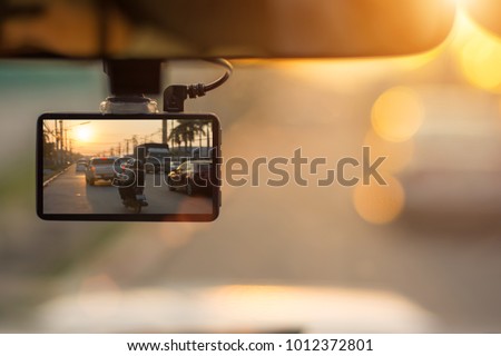 Close up car on highway at sunset, with video recorder next to a rear view mirror,video recorder driving a car on highway,car video recorder,Full HD camera recorder for vehicle.