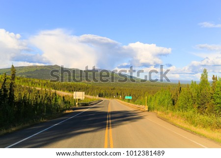 From North to South - driving on Elliot Highway through green hills to Fairbanks, Alaska.