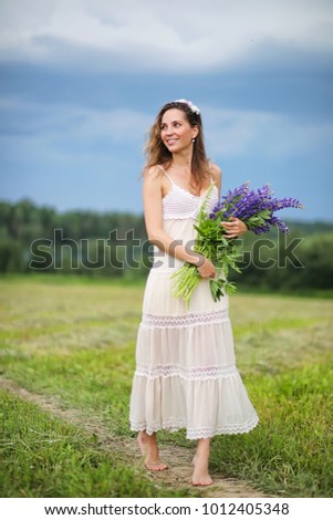 Beautiful girl with a bouquet of blue flowers on nature in summer