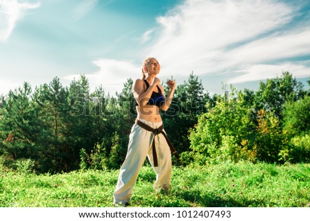 A beautiful girl in a kimono is engaged in a park. Martial arts.