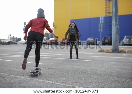A young hipster girl is riding a skateboard. Girls girlfriends for a walk in city with a skateboard. Spring sports on the street with a skateboard.