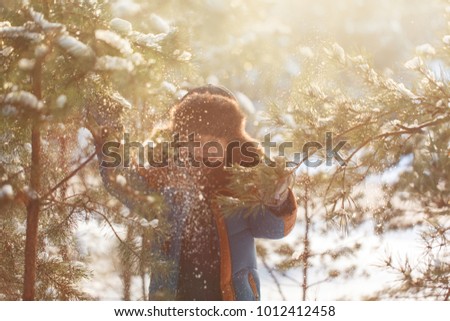 Happy child walking in a winter forest in sunny day.