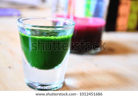 Wheat grass shot with beetroot juice in the background.
